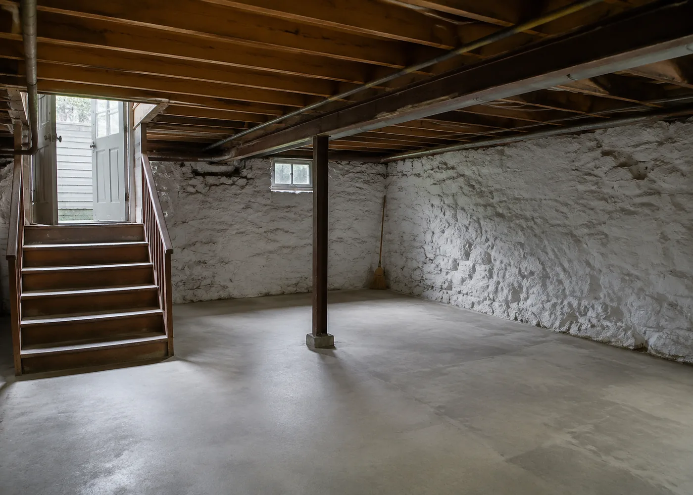 Empty basement with a swept concrete floor after a cleanout