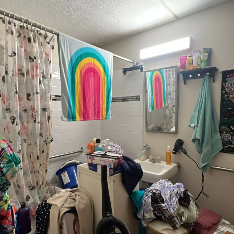 Bathroom crowded with laundry, bags and a vacuum in front of the tub before a cleanout