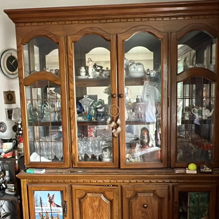 Wooden china cabinet filled with glassware and keepsakes