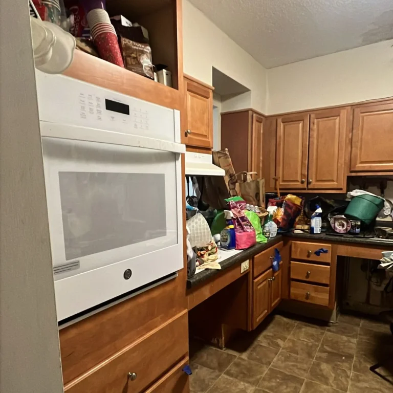 Kitchen counters and cabinets packed with bags, bottles and clutter before a cleanout