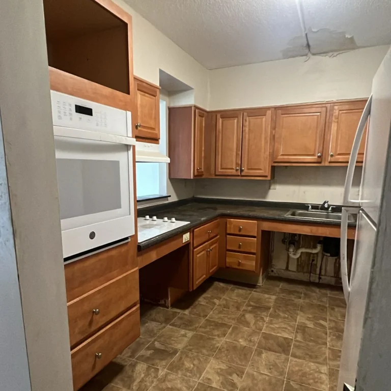 The same kitchen cleared out, counters bare and the refrigerator gone